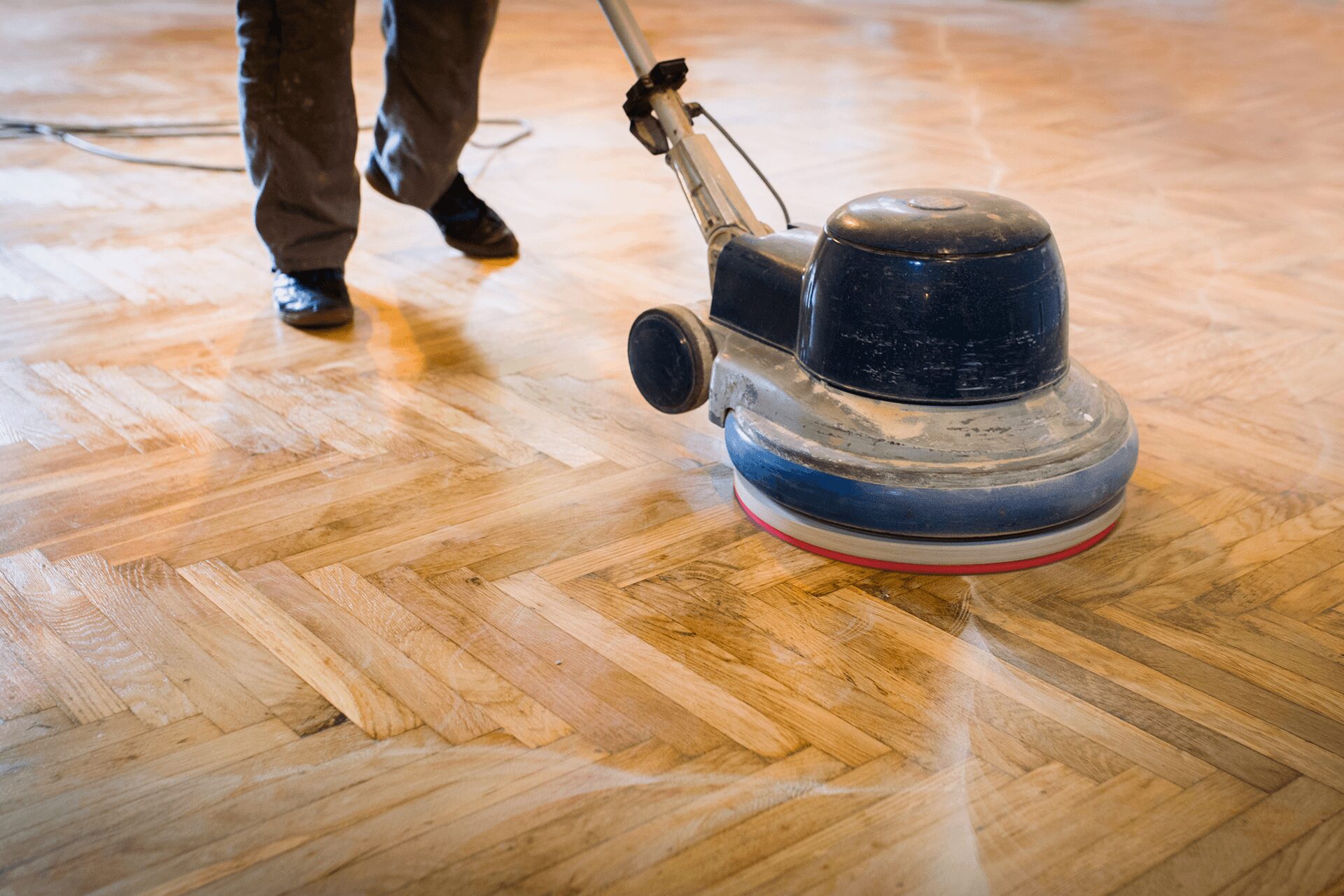 Person polishing wooden floor with machine.